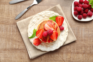 Plate with delicious pancakes on wooden background