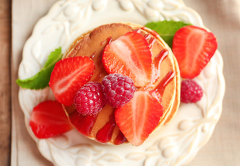 Plate with delicious pancakes on table