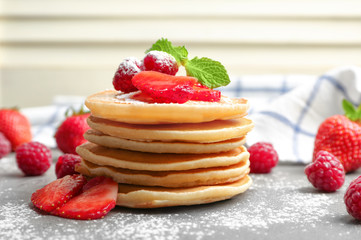 Delicious pancakes with raspberry and strawberry on table