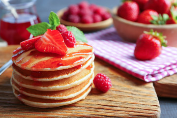 Delicious pancakes with raspberry and strawberry on wooden board