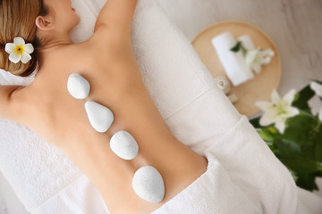 Young beautiful woman having stone massage in spa salon