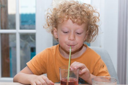 Cute Little Boy Is Drinking Red Juice Using Straw