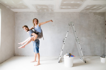 Young couple painting walls in their new house.