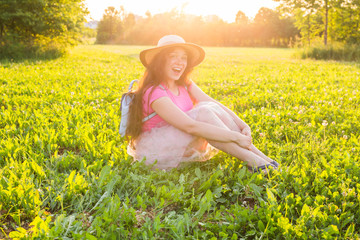 Beautiful young laughing naughty woman sitting on the grass and smiling