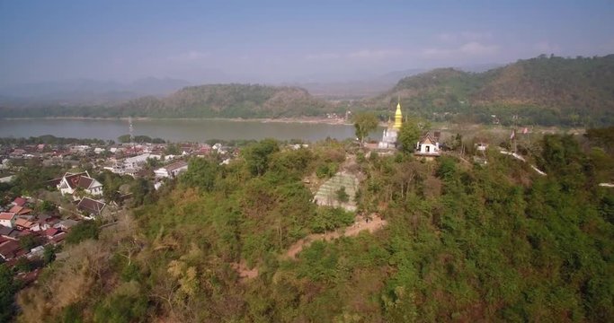 Mount Phousi And Wat Chomsi Golden Pagoda In Luang Prabang, Laos, Aerial Slider Shot
