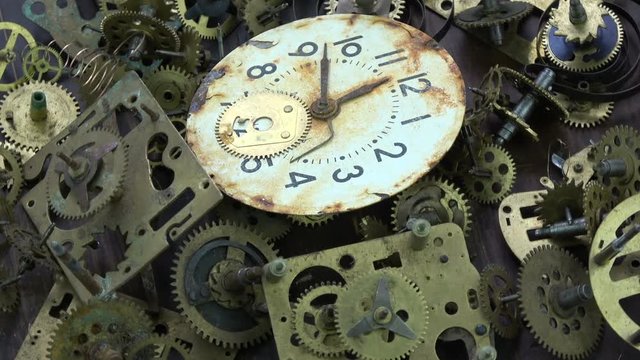 Vintage analog clock brass gears and cogs with rusty white dial clock face rotating background

