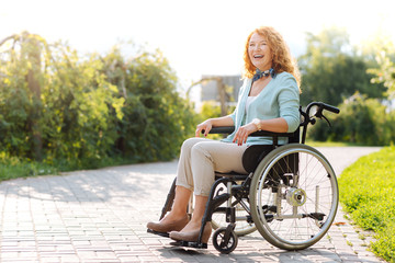 Chrerful wheelchaired woman laughing in the park
