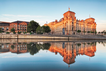 The Reichstag building (Bundestag) with reflection in river Spree early in the morning