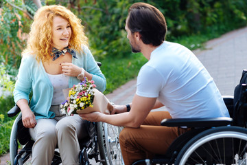 Cheerful wheelchaired woman getting a bunch of flowers