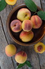 Wooden bowl with peaches on wooden background