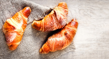 Tasty fresh croissants on a bright  wooden background. Top view.