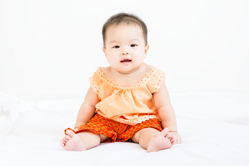 Fototapeta premium Portrait of adorable baby sitting on a white floor and smiling with copyspace