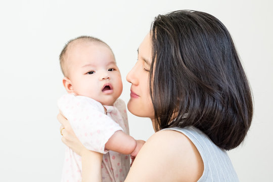 Portrait of happy asian mother kissing and hugging her cute little baby