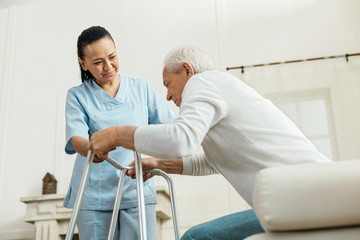 Joyful nice woman helping an elderly man