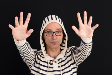 attractive candid european middle-aged male in hooded sweater with calm down gesture - studio shot on black background