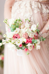 Pregnant girl in a beige dress with a bouquet in hands. Natural. Waiting for a miracle.
