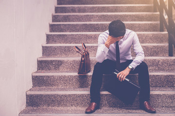 Fototapeta stressed businessman holding portfolio sitting at stairway. disappointed for job search obraz