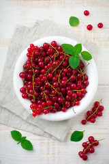 Raw juicy and fresh berries of red currant and mint leaves in  white plate. Selective focus. Top view.