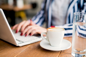 Focused cup of coffee while businesswoman is having a break in a cafe.
