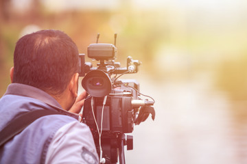 Cameraman using professional digital video camera. Outdoor setup and working