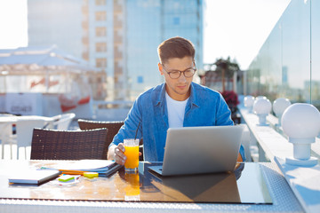 Young freelancer working on laptop outdoors