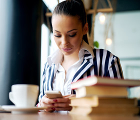 Serious beautiful businesswoman is holding mobile while coffee break.