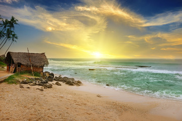 old fisherman's hut on shore of picturesque ocean and beautiful sunset