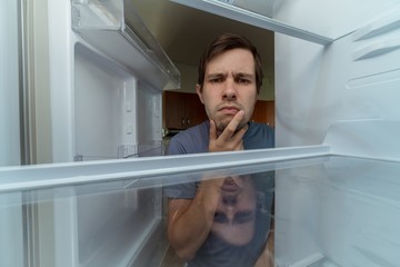  Hungry man is looking for food in empty fridge.