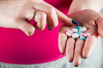 Young girl mixing pills and vitamins by finger on her palm, horizontal image