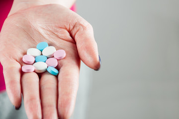 A young girl holding pills and vitamins in the palm, horizontal image