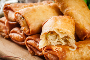 Spring rolls with chicken and vegetables on chopping board