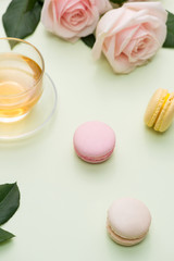 French macaroons. Many variegated sweet macarons in box with bouquet of pink roses on the table