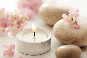 Fototapeta na wymiar SPA still life with pebbles, flowers and aromatherapy candles