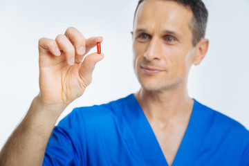Positive minded doctor looking at red pill