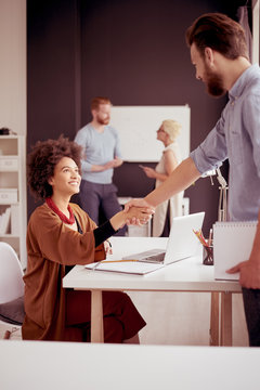 Businessman shaking hands with colleague while standing in modern office