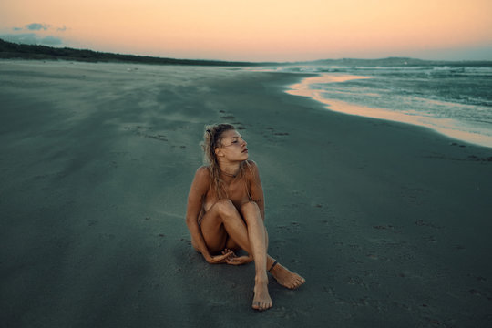Naked woman sitting on the beach 