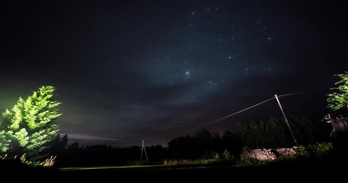 Timelapse of stars over trees at summer night then clouds coming on dark sky. Timelapse. Starfall. Milky way. Tree on the foreground.