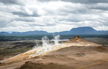Mudpot in the Namafjall geothermal area, Iceland - area around boiling mud is multicolored and cracked