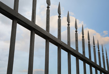 Beautiful wrought fence against blue sky. Image of a decorative cast iron fence. metal fence close up. Metal Forged Fence.