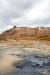 Mudpot in the Namafjall geothermal area, Iceland - area around boiling mud is multicolored and cracked