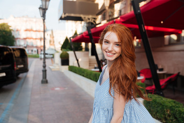 Smiling redhead girl standing outside on a city street