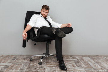 Happy drunk businessman sitting in office chair with bottle