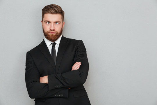 Funny bearded man in suit standing with eyes crossed