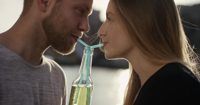 Close shot of sweet couple drinking lemonade with a straw