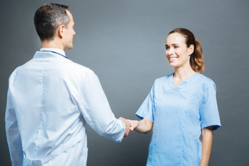 Friendly female doctor shaking hands with male colleagues