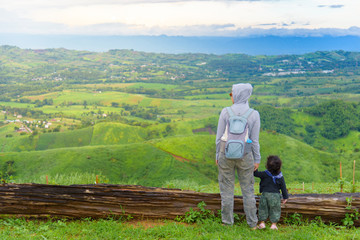 Happy mother holding daughter hands relax with blue sky and mountain landscape. Adventure travel of parent and kid.