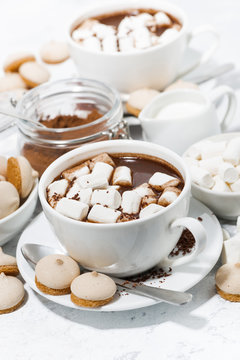 cups of hot chocolate with marshmallows on white table, vertical