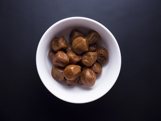 Umeboshi plums from Japan in white bowl, fermented and salted and placed in a honey syrup. Isolated on black background