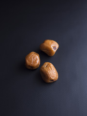 Umeboshi plums from Japan, fermented and salted and placed in a honey syrup. Isolated on black background
