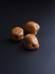 Obraz premium Umeboshi plums from Japan, fermented and salted and placed in a honey syrup. Isolated on black background